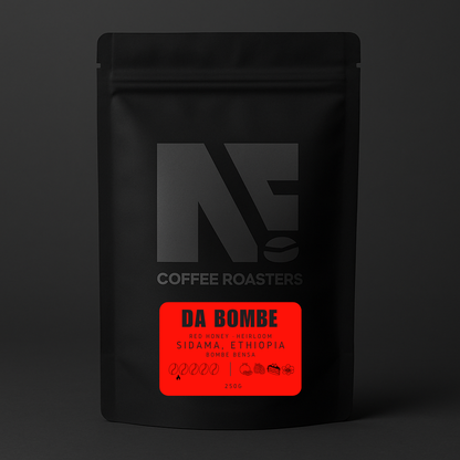 Black coffee bag with a red label featuring 'DA BOMBE' on a dark background